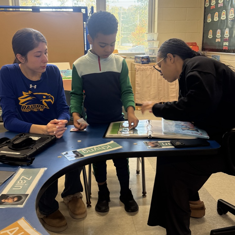 High school students helping a little kid play with a puzzle