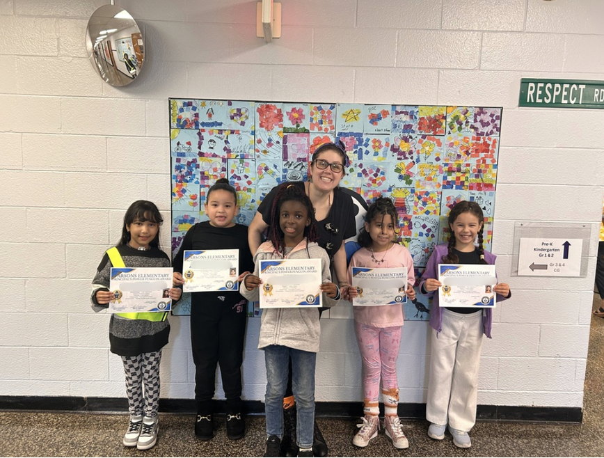 Principal standing with students with certificates