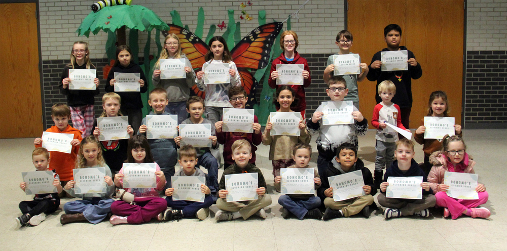 three rows of students sitting, kneeling or standing holding certificates