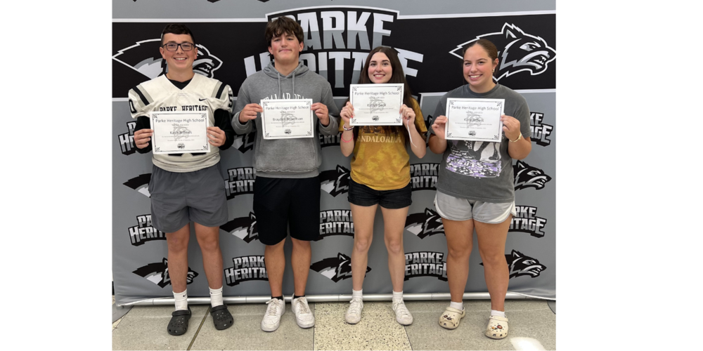 four students standing in front of a back drop and holding certificates