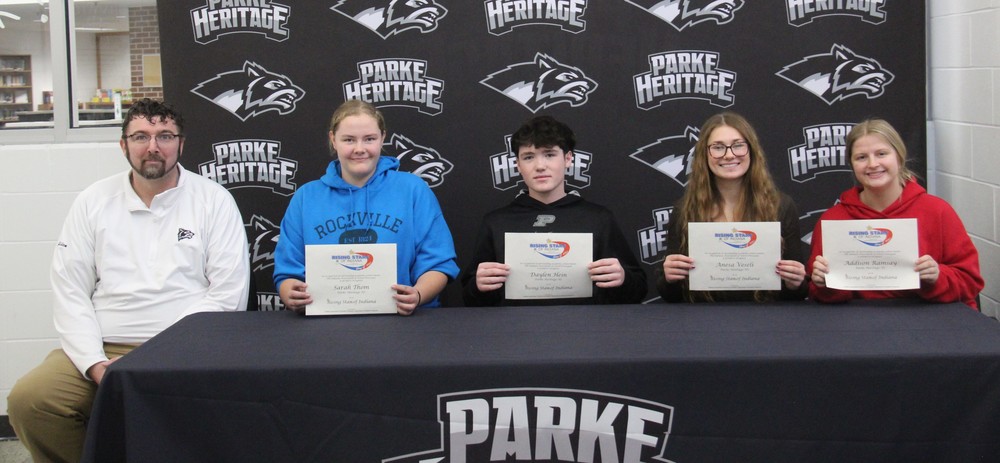 principal along with four students sitting at a table holding certificates