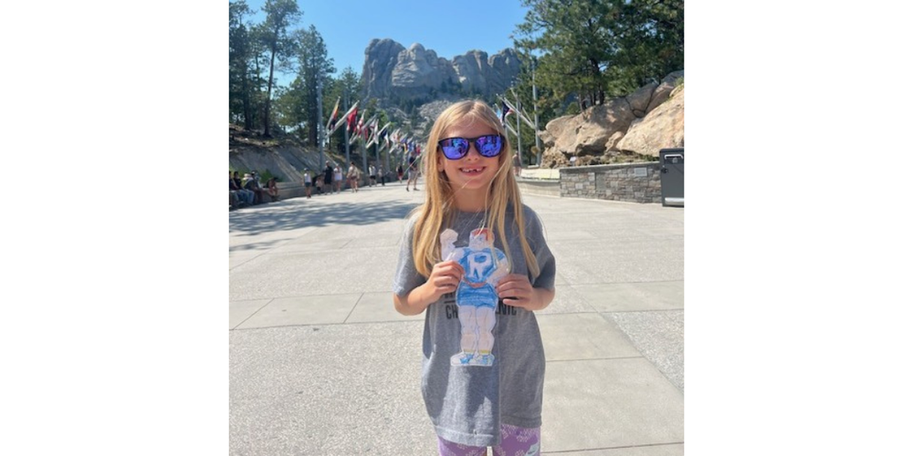 girl standing in front of Mount Rushmore holding the Rox man