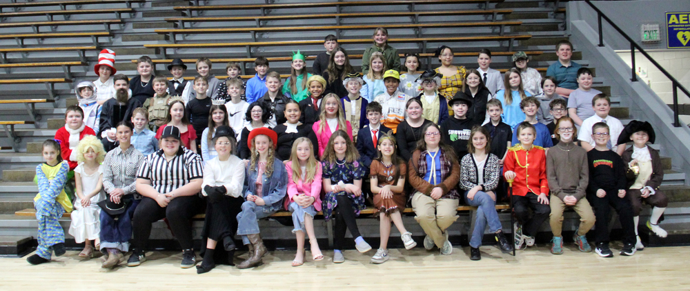 five rows of students sitting in the gym bleachers wearing costumes