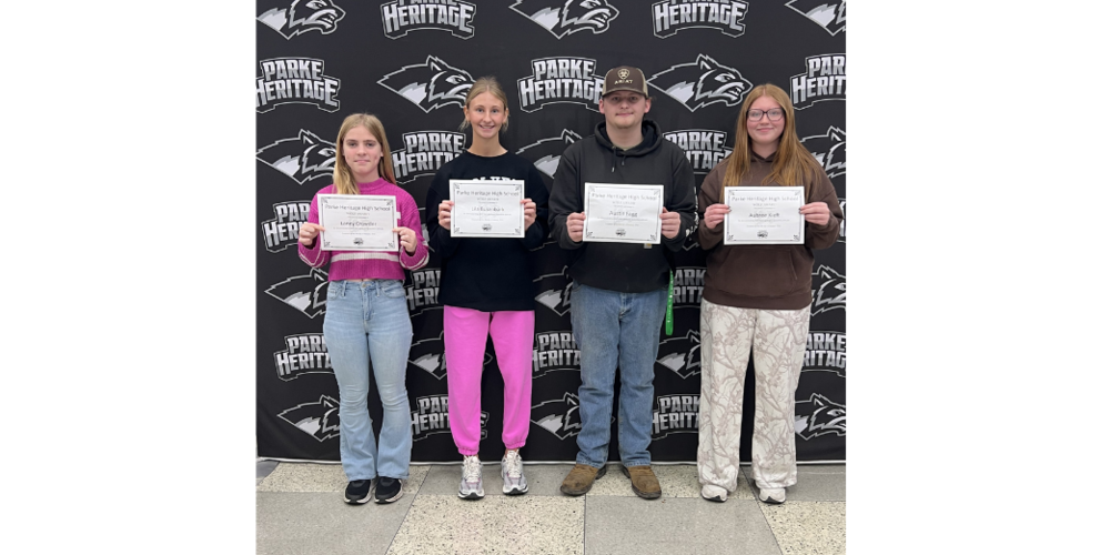 four students standing in front of a backdrop holding certificates