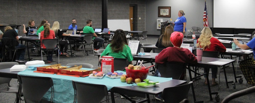 middle school staff members sitting at tables and listening to the principal