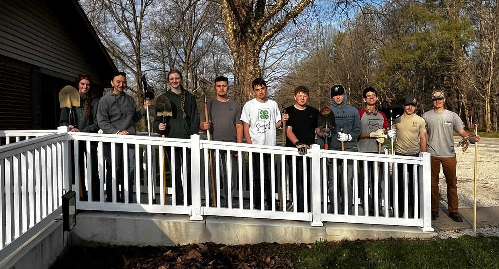 10 students standing on a ramp holding yard utensils