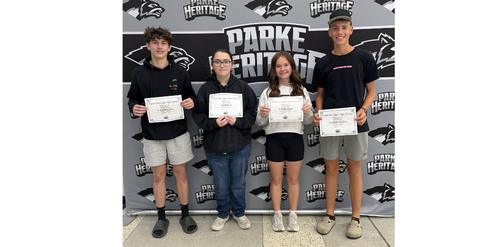 four students standing against a backdrop holding certificates