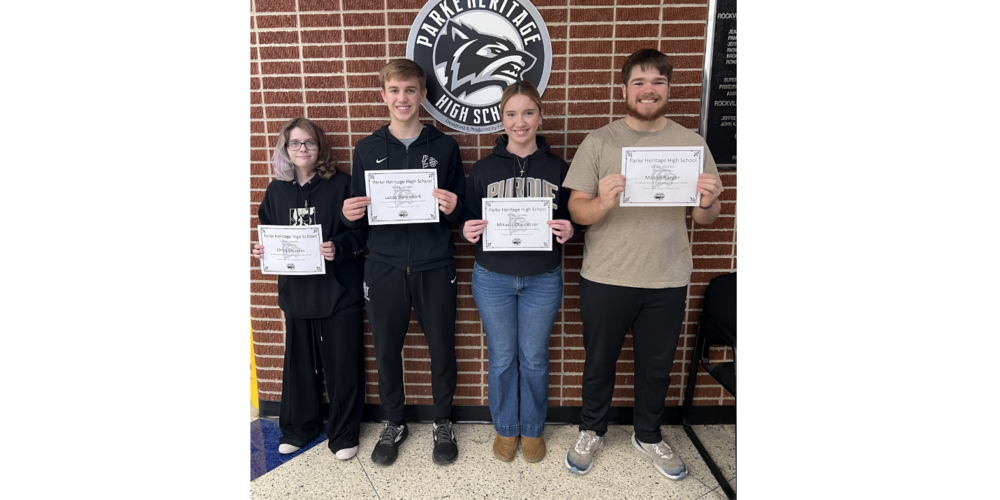 photo of four students standing in a line holding certificates