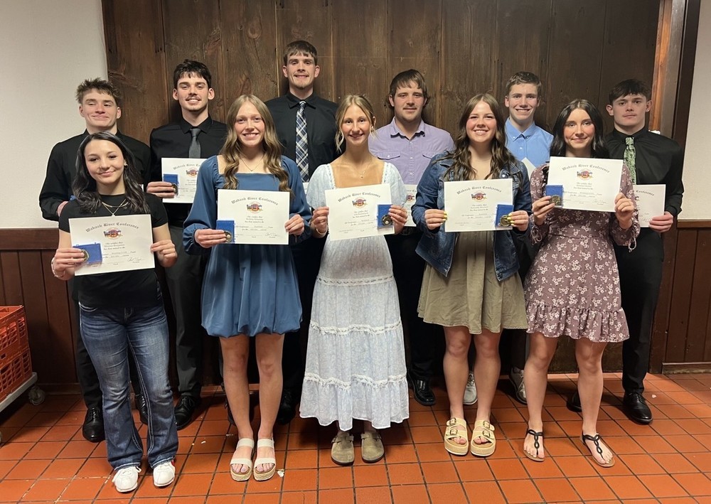 11 athletes standing in two rows holding certificates