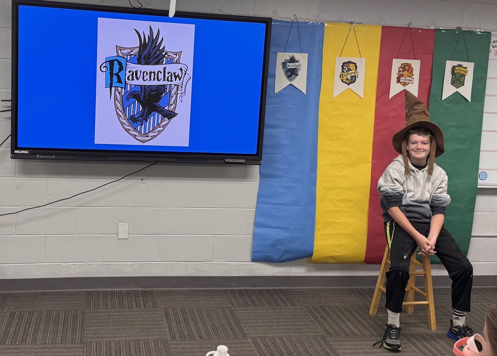 student sitting on a stool wearing a sorting hat