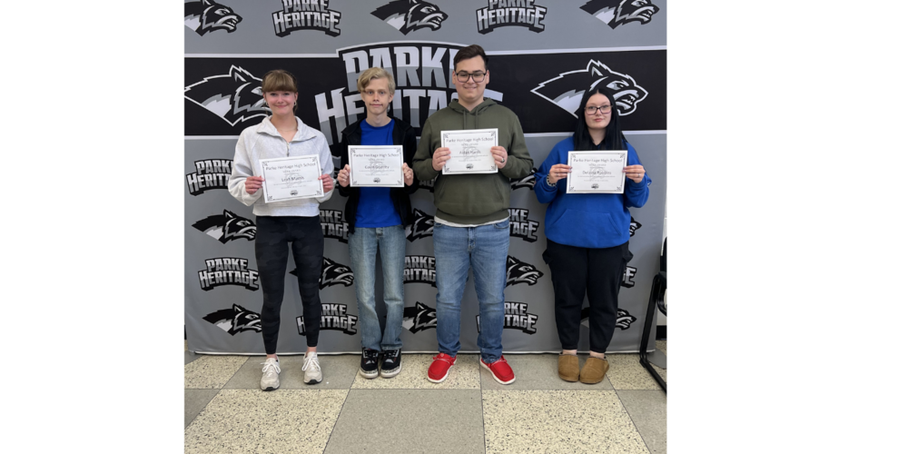 four students standing in a line holding certificates