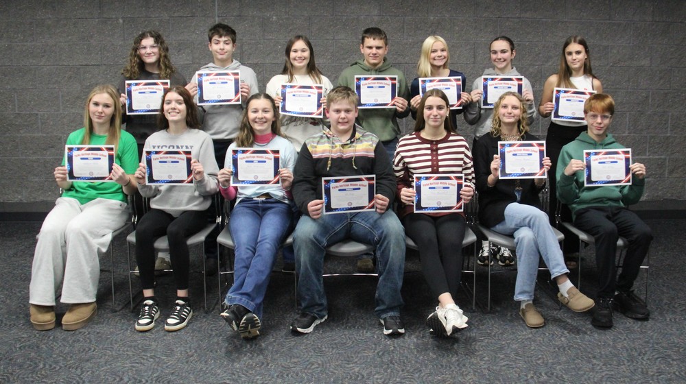 two rows of students sitting and standing and holding certificates