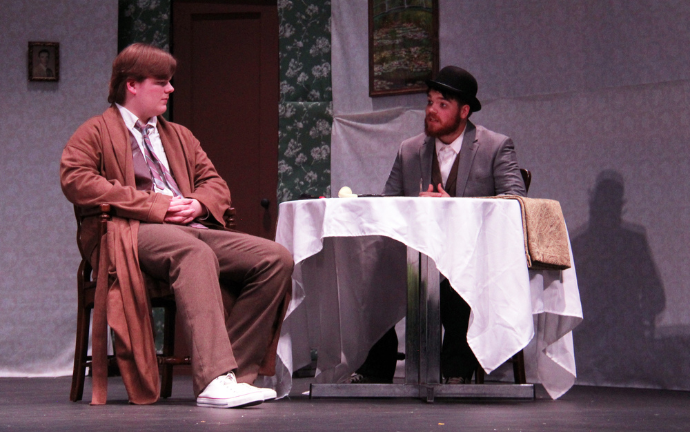 two boys sitting at a table on the stage