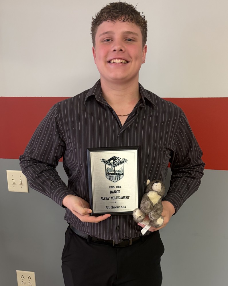 dance team member holding a plaque and a stuffed wolf animal