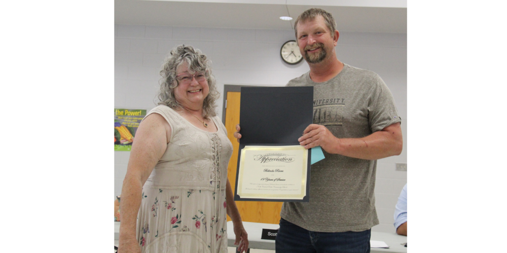 two people standing with one of them holding a certificate