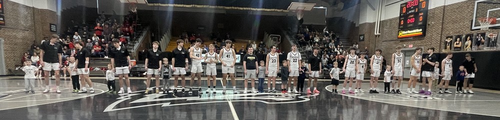 line of high school basketball players standing in a line with their kindergarten buddies in the gym