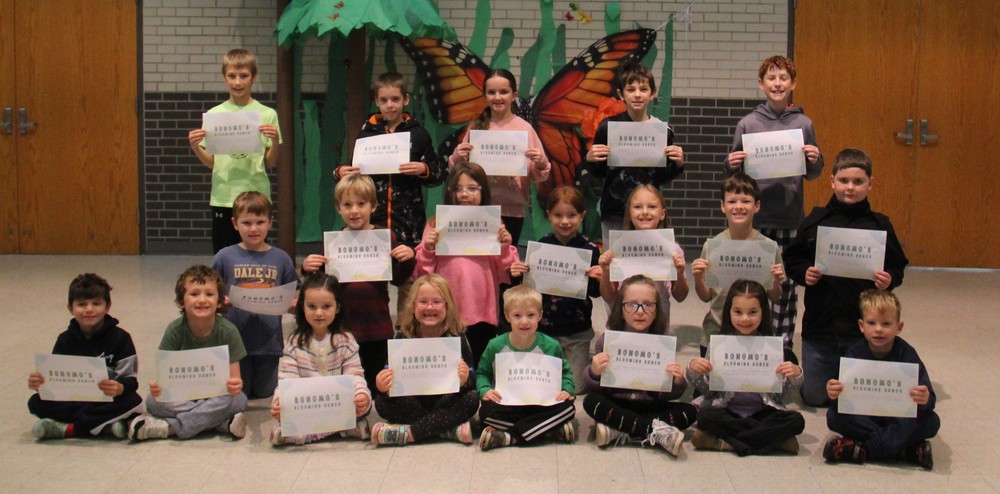 three rows of students sitting, kneeling and standing while holding certificates