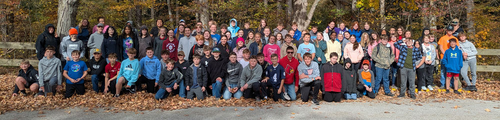 students sitting, kneeling and standing in a group on their field trip