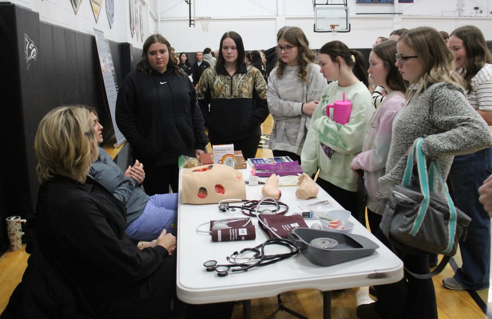 students standing around a table listening to the health care instructors