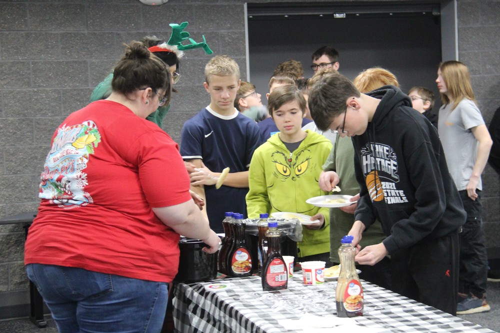 staff serving pancakes to students