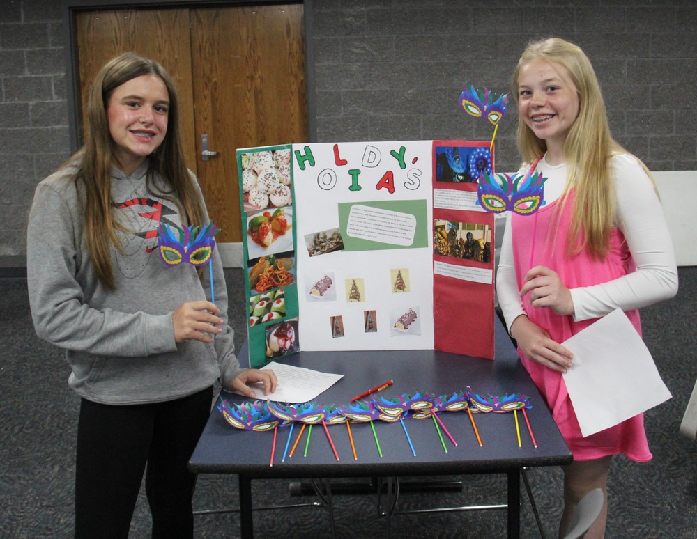 2 girls with a display board on Italy and holding masks