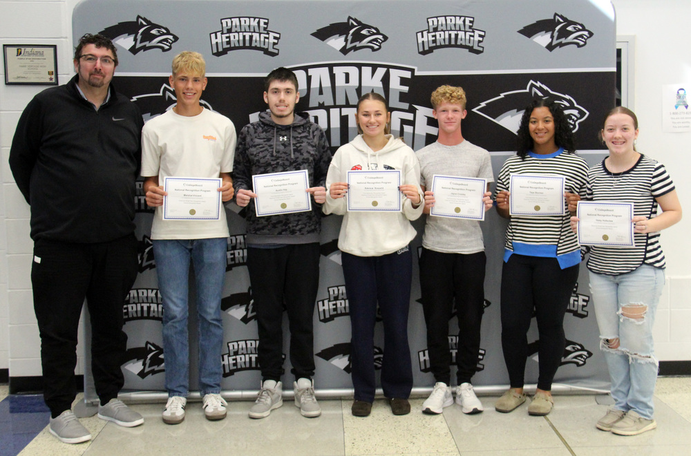 six students standing and holding certificates along with the HS principal