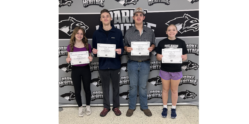 four students standing in front of a back drop holding certificates
