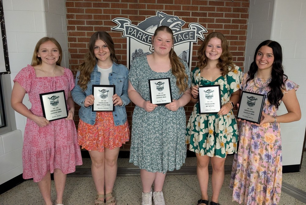 five girls standing in a line holding plaques