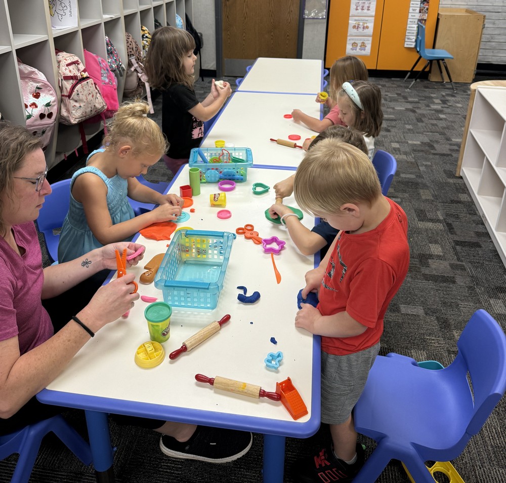 preschool students sitting at a table doing crafts