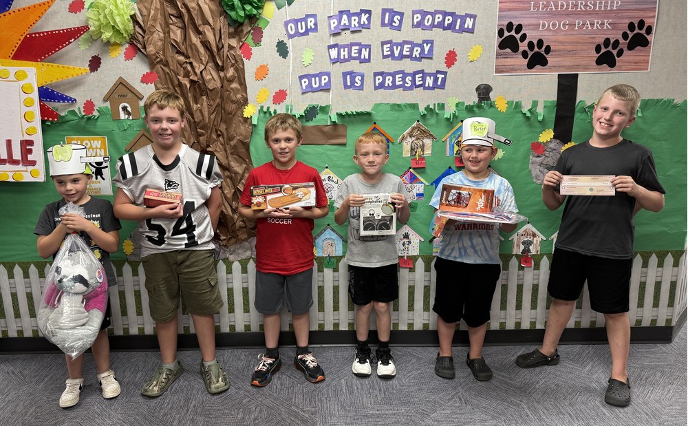 six students standing along a wall with their trashbag prizes