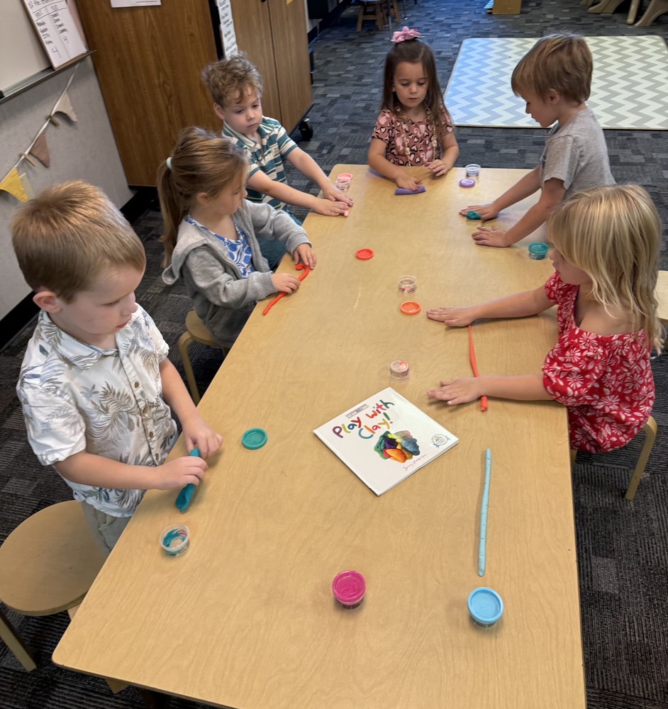 students sitting around a table playing with Play-Doh