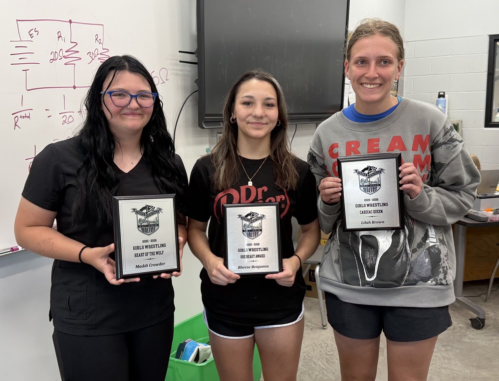 three girls standing in a row holding plaques