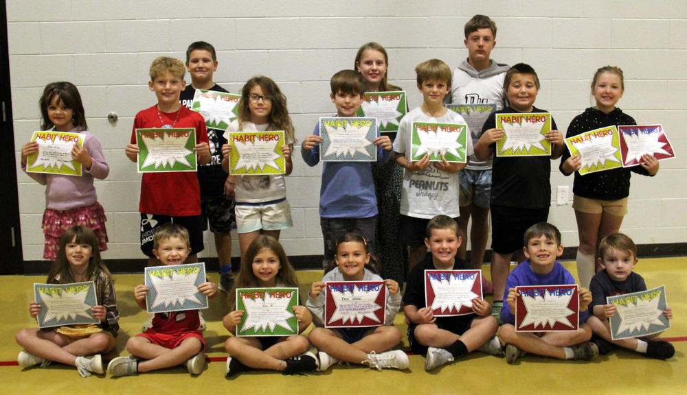 students sitting or standing on the gym floor holding certificates
