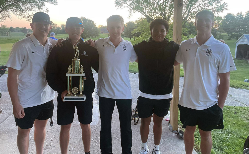 photo of five golfers standing in a line with one of them holding a trophy