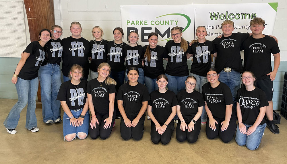 two rows of cheerleaders and dance team members sitting or standing in front of a banner at the Parke County REMC dinner