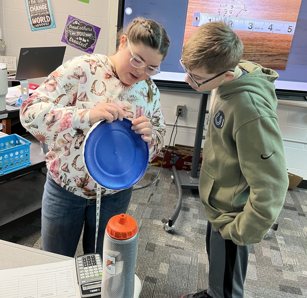 two students trying to measure a paper plate