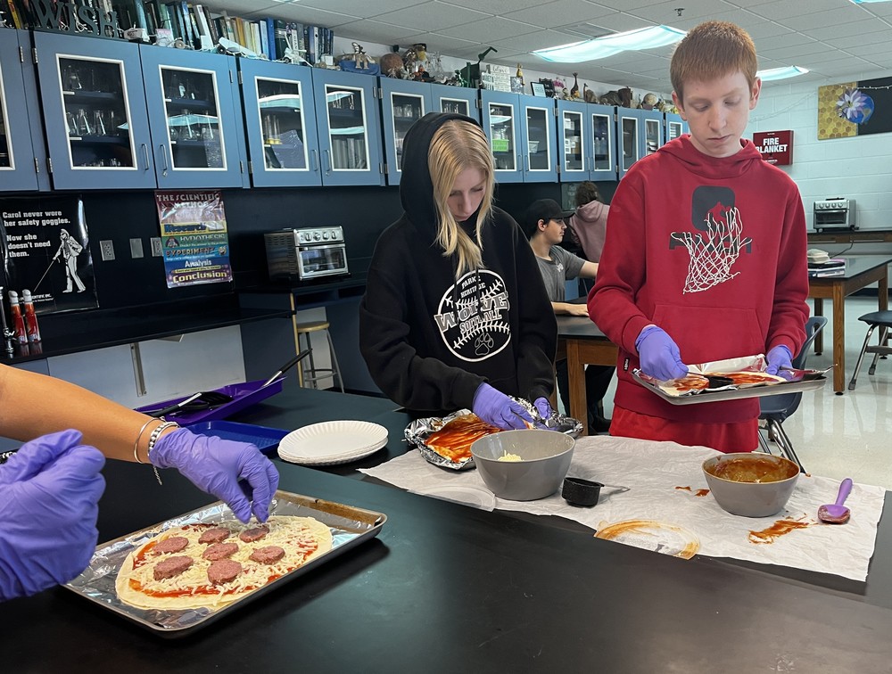 students making pepperoni pizzas