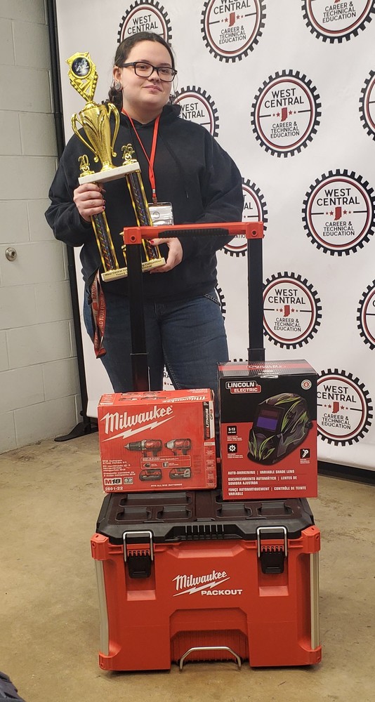 a student holding a certificate with prize boxes in front of her