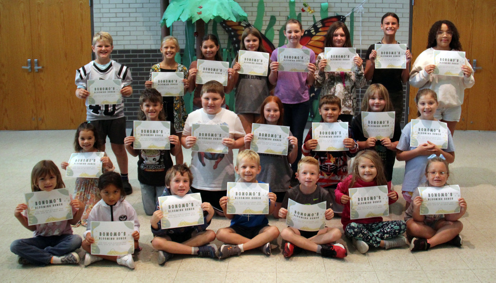 three rows of students sitting, kneeling or standing holding certificates