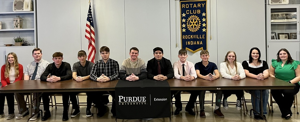 12 students sitting at a table in a row