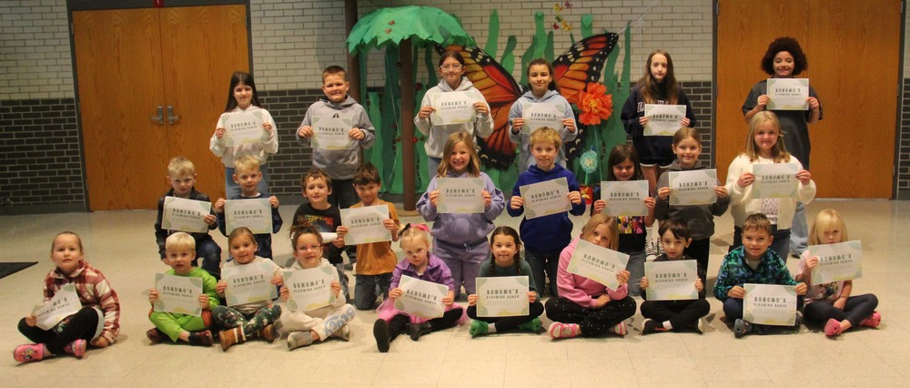 three rows of students sitting, kneeling or standing and holding certificates