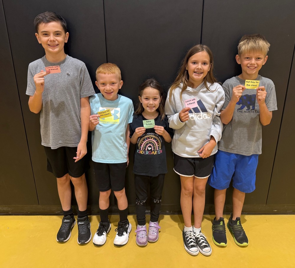 five students standing against a wall and holding lotto tickets