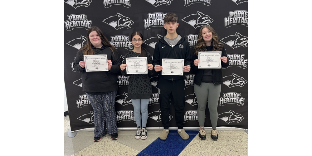 four students standing in front of a backdrop holding certificates