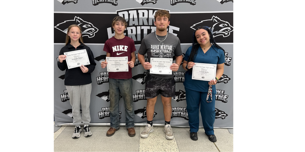 four students standing in front of a backdrop holding certificates