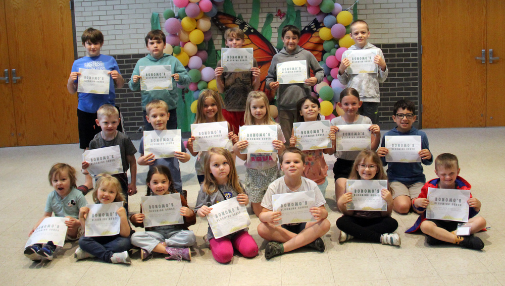 three rows of students sitting, kneeling and standing and holding certificates