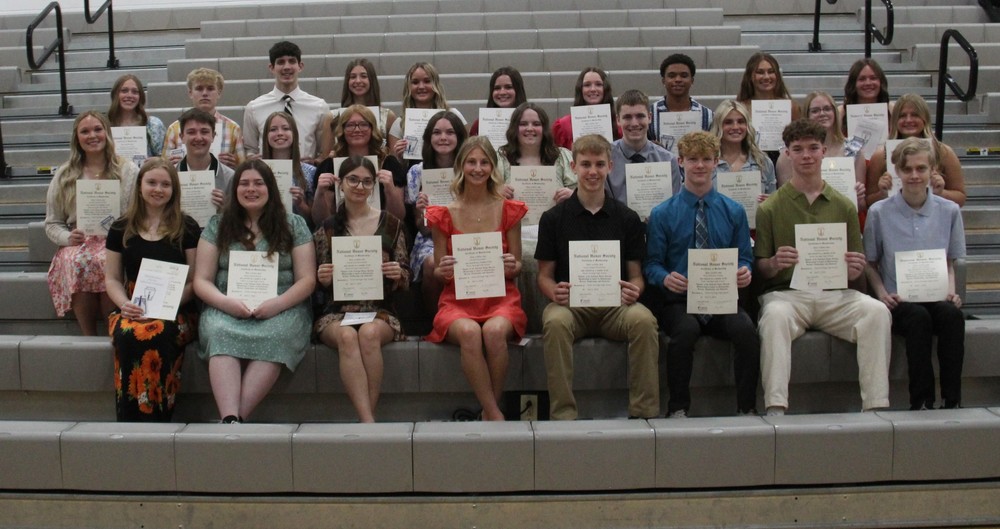 three rows of students sitting in rows holding certificates