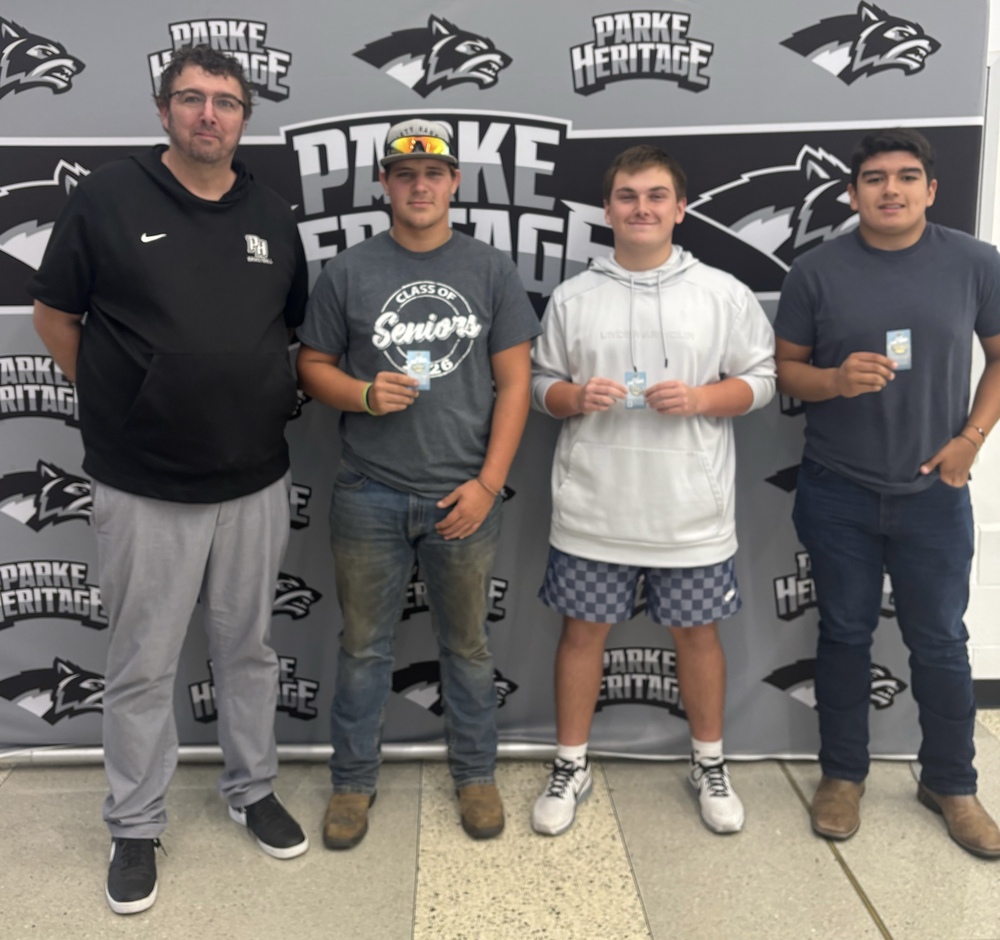 HS principal with three football players holding pins