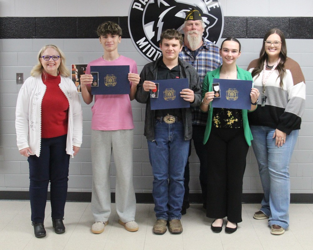six people standing in a row with three of them holding certificates