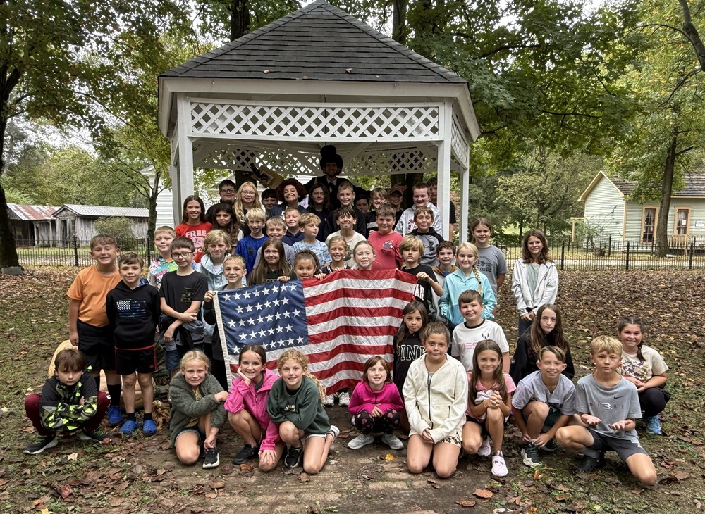 students sitting or standing by a gazebo with an Abraham Lincoln speaker