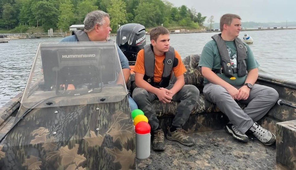 three men on a boat wearing life jackets